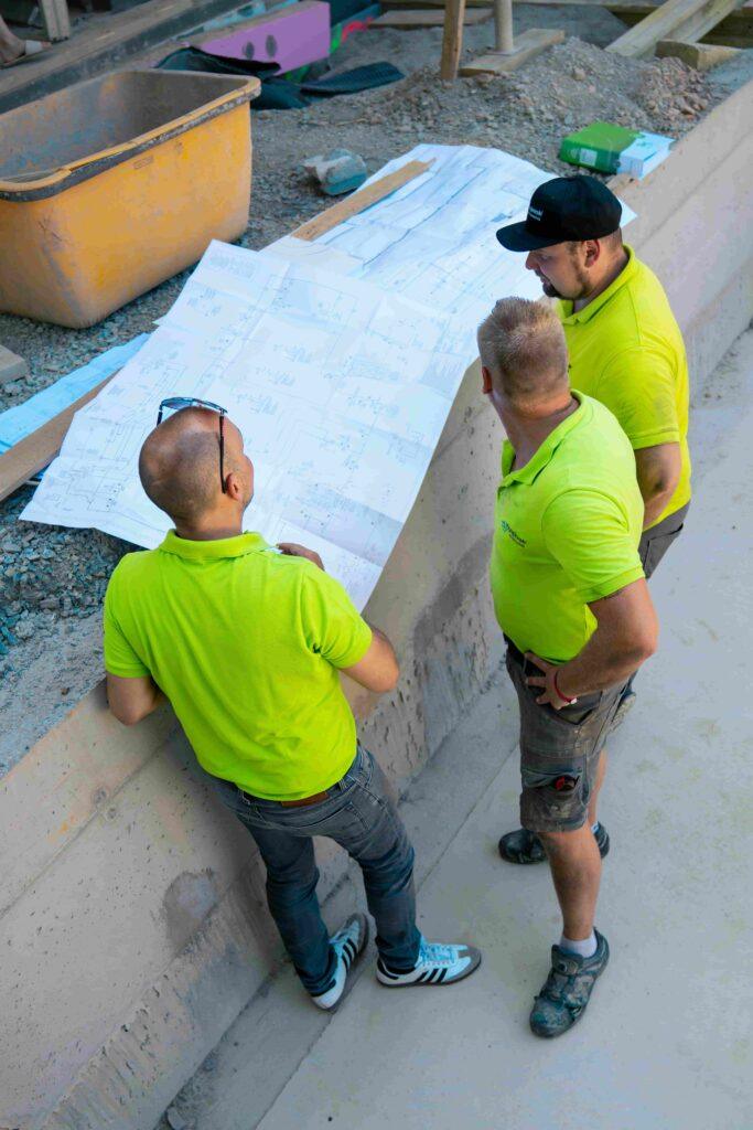 Drei Arbeiter der Papajewski GmbH schauen auf Baupläne