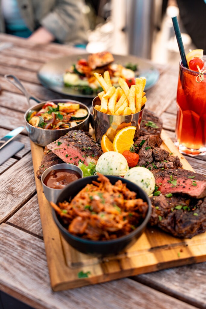 Ein mit Pommes, Pulled Pork Gemüsepännchen und Steak angerichteter Beef-Teller